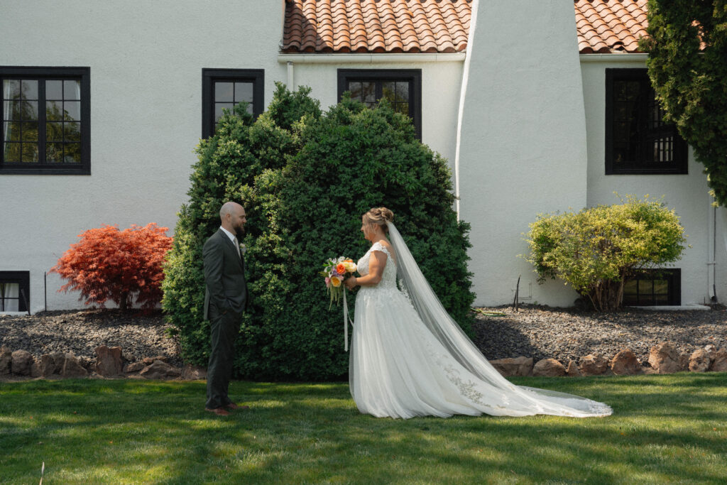 Bride and groom smiling during first look at The Cottage at River Bend in Eagle, Idaho.