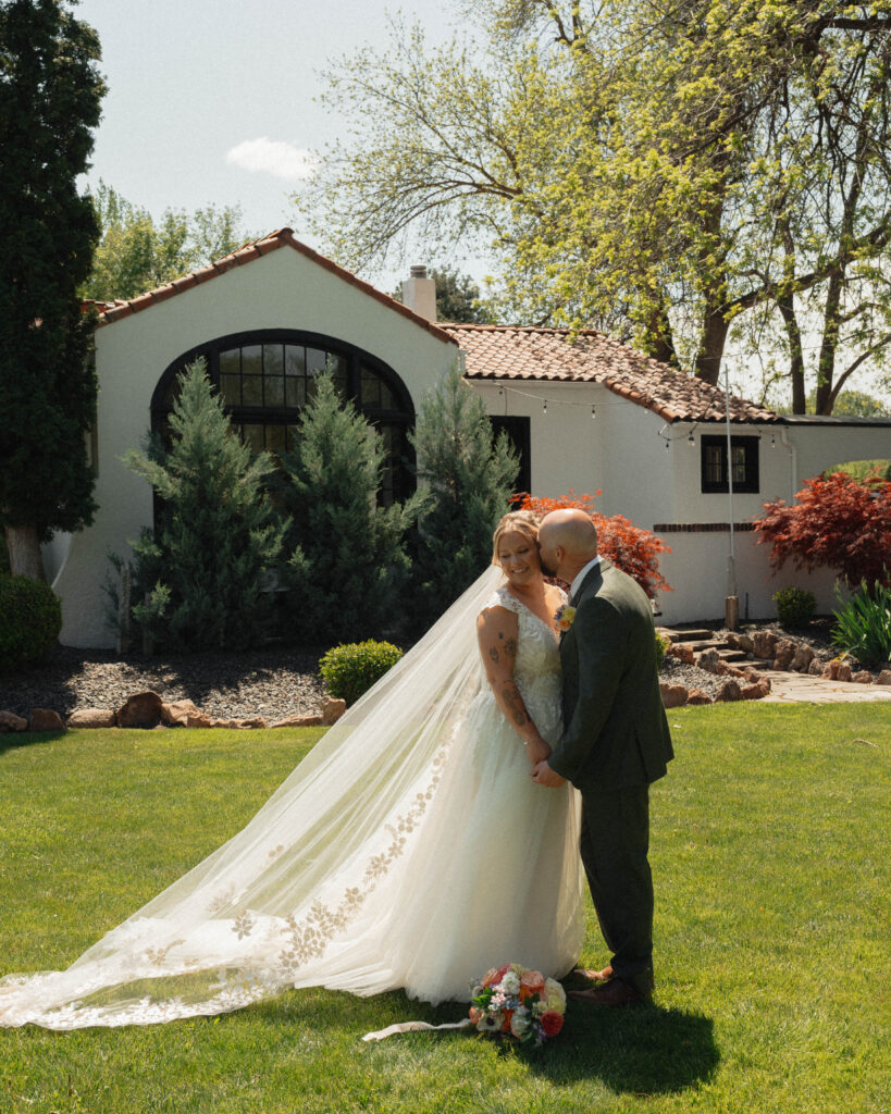 Bride and groom embracing on the lawn at The Cottage at River Bend in Eagle, Idaho.