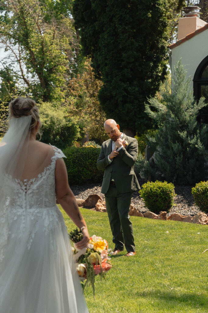 Bride standing with seated groom by arched windows at The Cottage at River Bend in Eagle, Idaho.