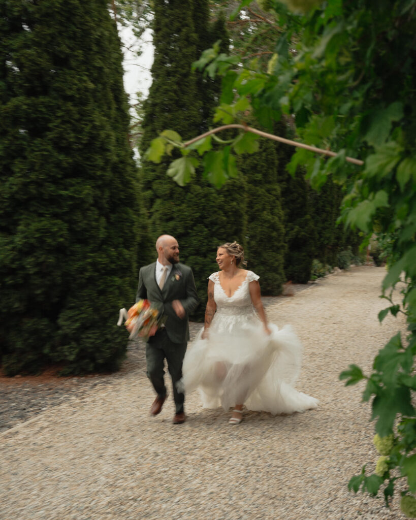 Bride and groom laughing while running on gravel path at The Cottage at River Bend in Eagle, Idaho.
