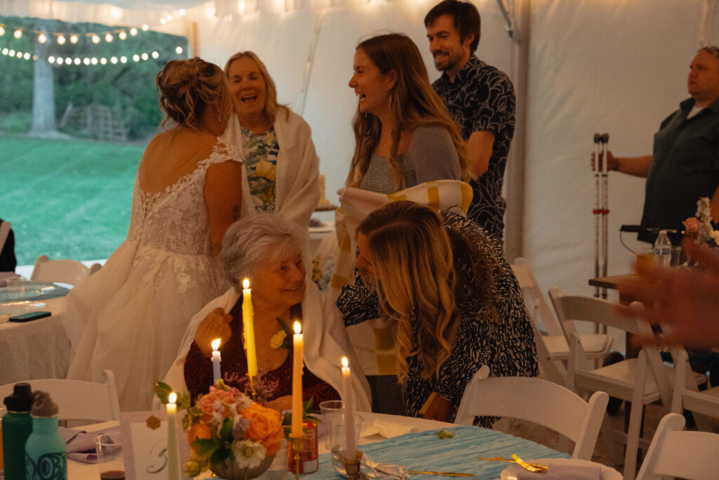 Bride greeting guests at candlelit reception inside tent at The Cottage at River Bend in Eagle, Idaho.