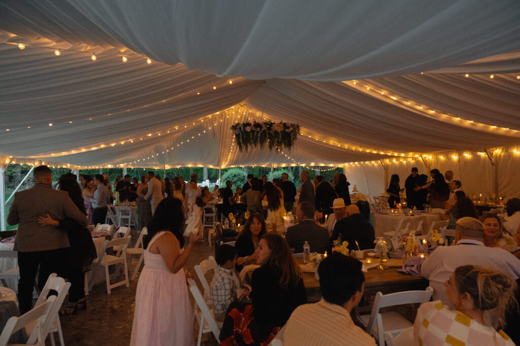 Bride greeting guests at candlelit reception inside tent at The Cottage at River Bend in Eagle, Idaho.