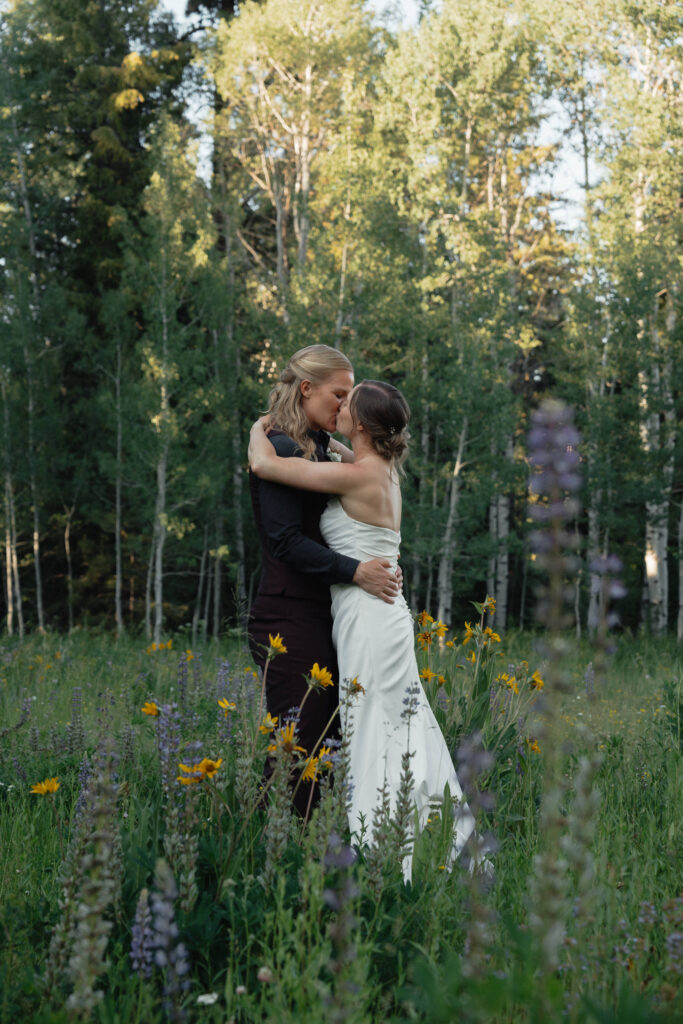 Bride and Bride embracing in a meadow at Tamarack Resort in Donnelly, ID