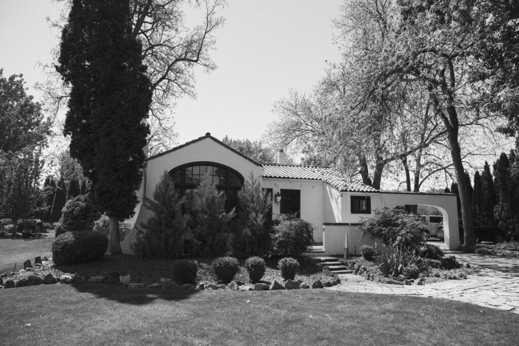 Black and white exterior of The Cottage at River Bend in Eagle, Idaho surrounded by trees.